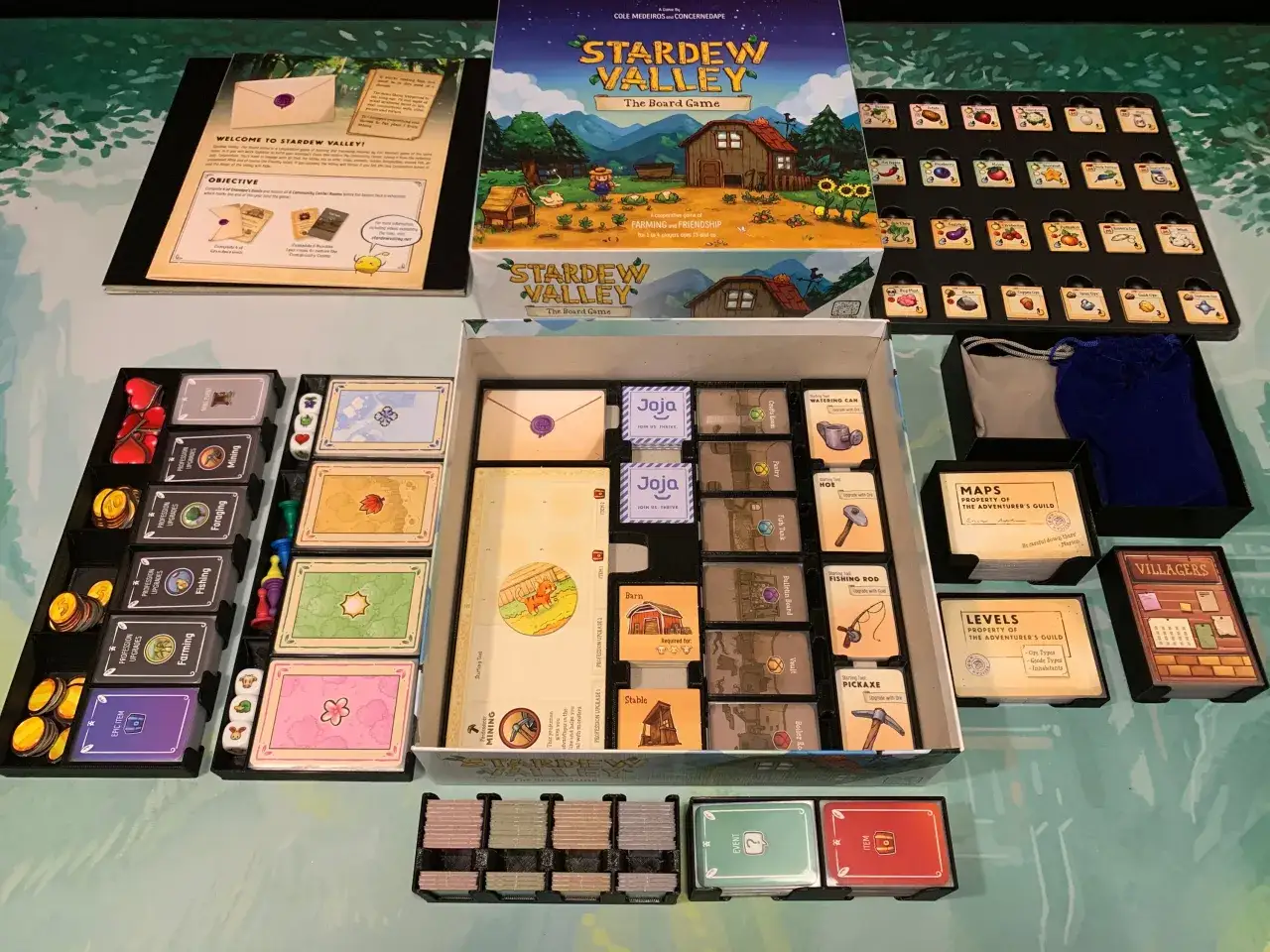 Stardew Valley gra planszowa rozłożona na stole, z widocznym pudełkiem, kartami, żetonami i planszą.