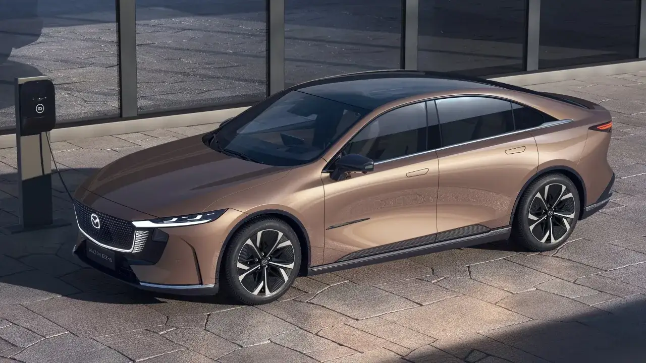 Elegancka, brązowa Mazda 6 EZ-6 z 2025 roku ładuje się przy nowoczesnej stacji ładowania.