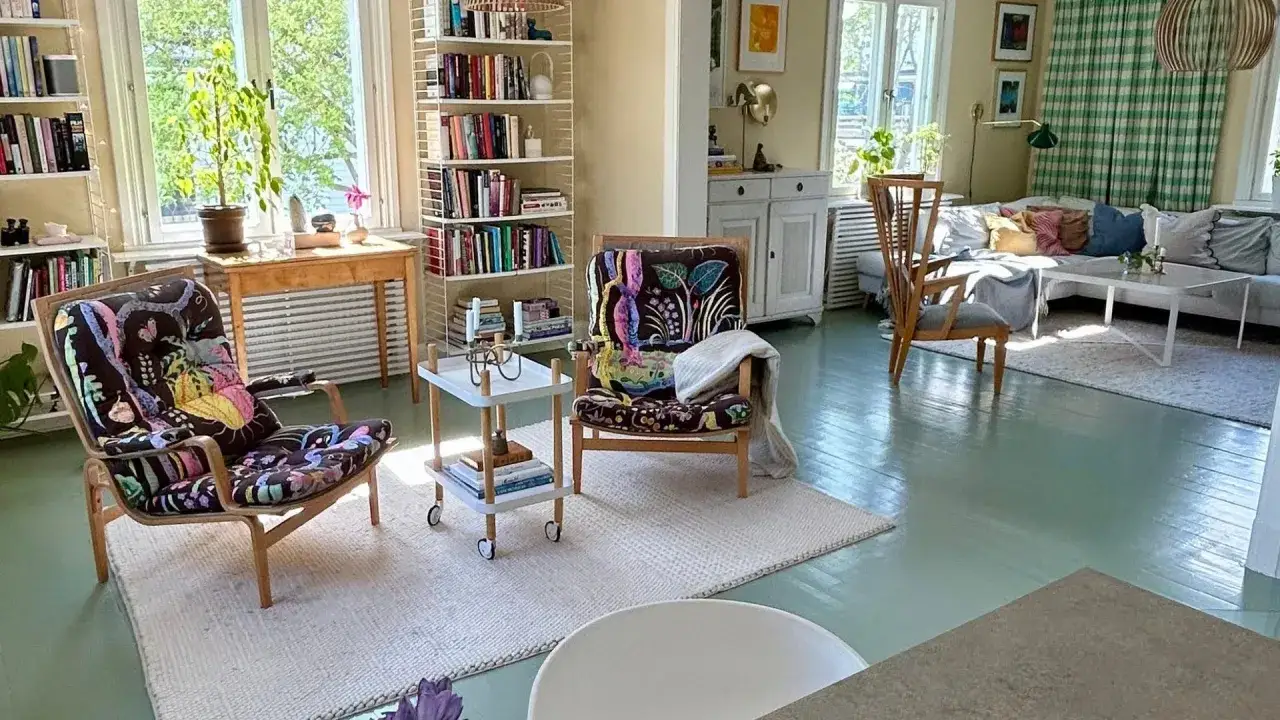 Ljust och luftigt vardagsrum med bokhyllor, bekväma fåtöljer med färgglada tyger och en soffgrupp. En känsla av harmoni som passar bra för feng shui vardagsrum.