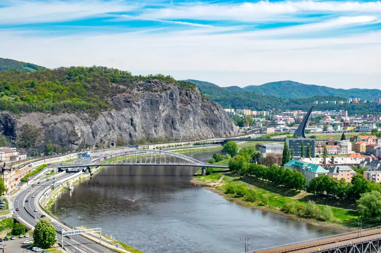 Blick auf die Stadt &Uacute;st&iacute; nad Labem mit Fluss, Br&uuml;cken und gr&uuml;nen H&uuml;geln im Hintergrund.