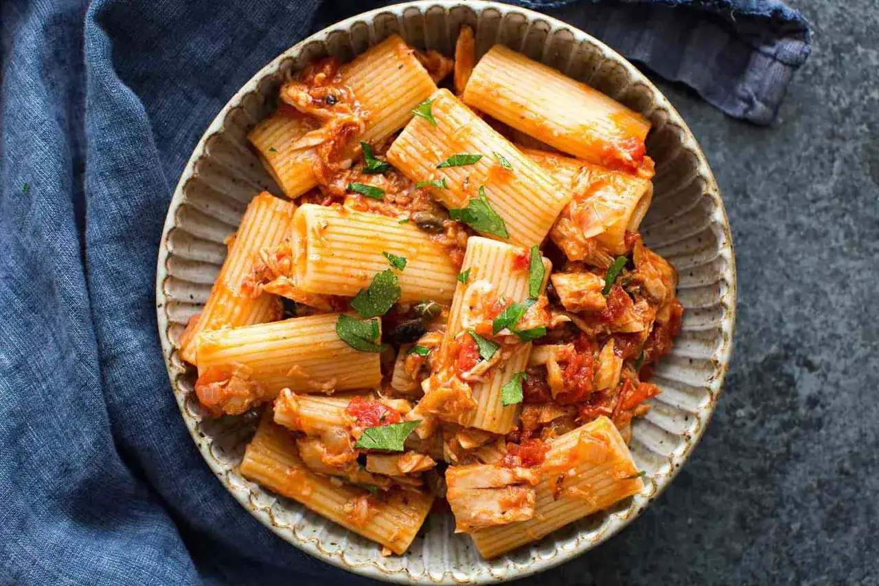Herzhafte Thunfisch Pasta mit Tomatensauce und frischer Petersilie in einer rustikalen Sch&uuml;ssel.