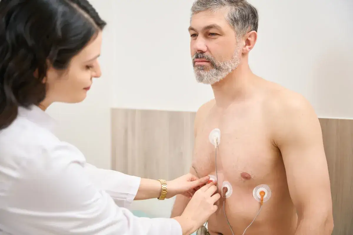 Lekarka przyczepia elektrody do klatki piersiowej pacjenta. Holter służy do długoterminowego monitorowania pracy serca.
