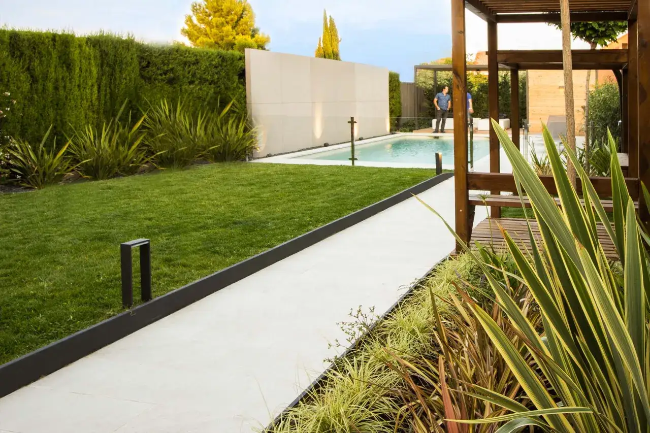 Modernos planos de jardines con piscina, c&eacute;sped impecable, setos altos y p&eacute;rgola de madera.