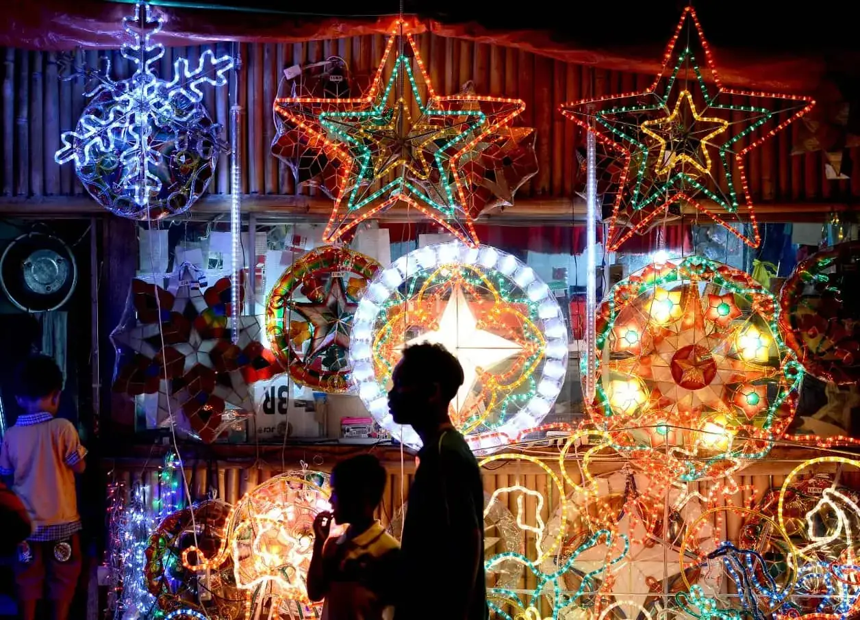 Bunte Lichterketten und Sterne schmücken einen Stand. Kinder bestaunen die Dekorationen, die die festliche Stimmung der Philippinen zu Weihnachten widerspiegeln.