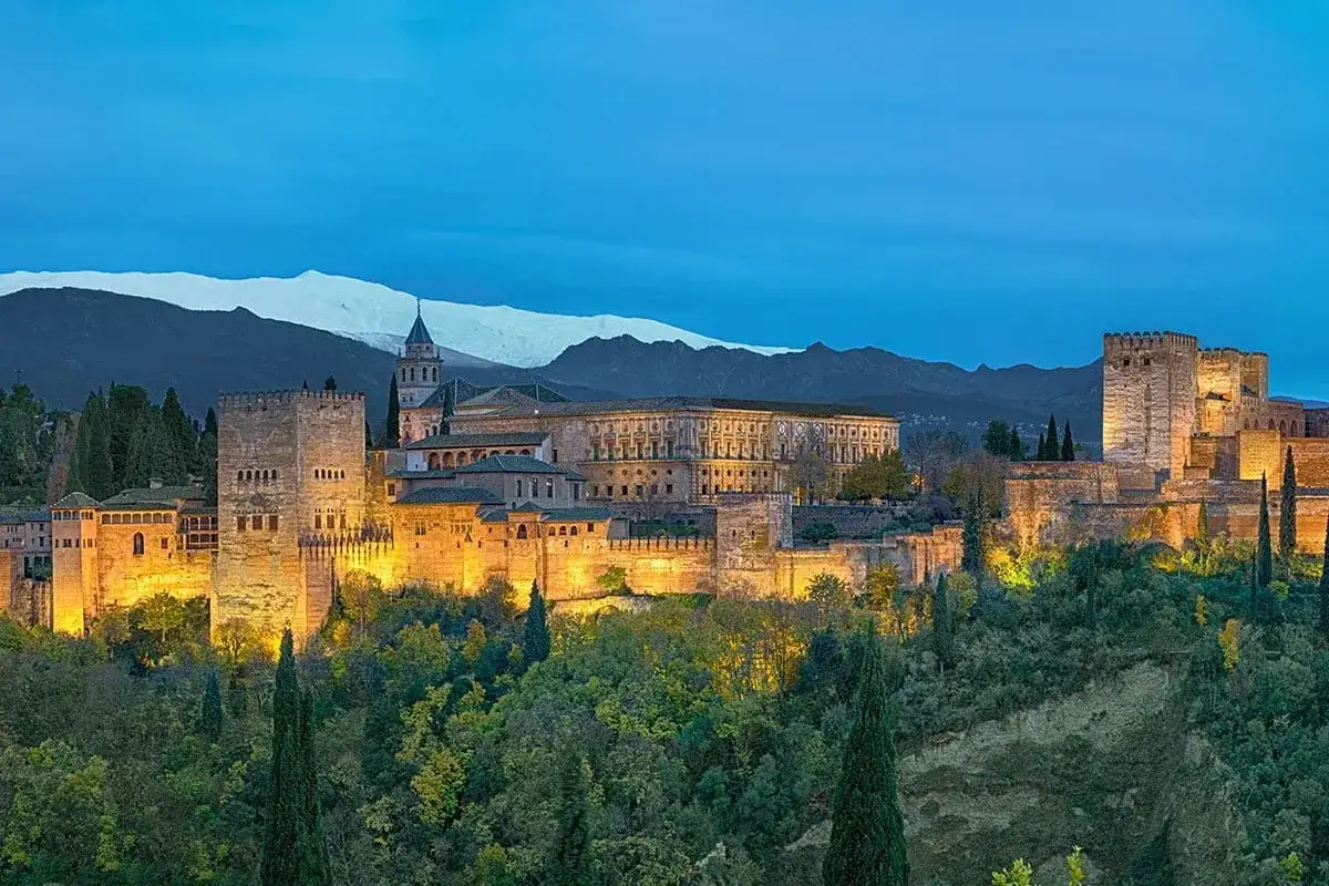 Granada co zobaczyć: oświetlona Alhambra na tle ośnieżonych gór. Niezapomniany widok!