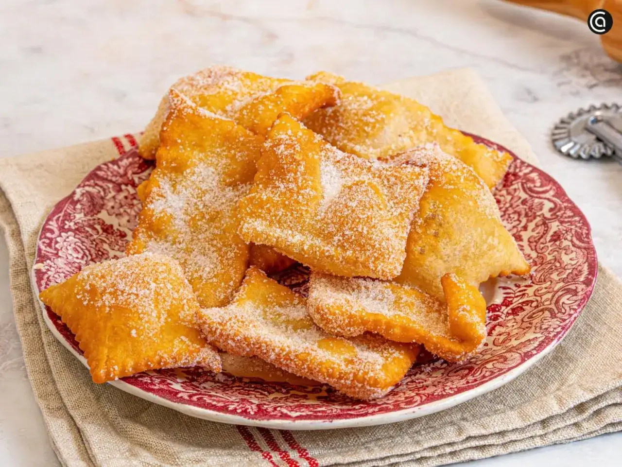 Deliciosas hojuelas fritas espolvoreadas con azúcar, listas para ser bañadas en miel. Un dulce placer que evoca la infancia.