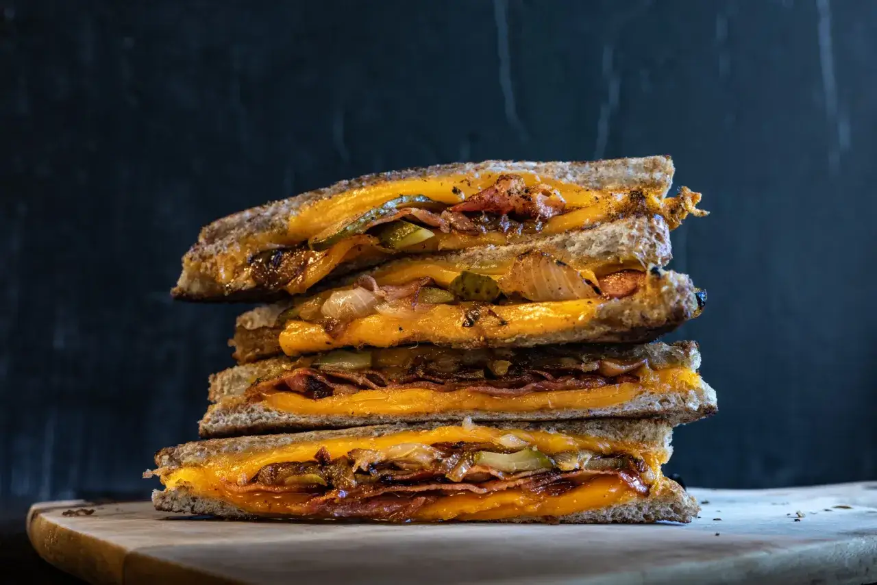 Gestapelte gegrillte K&auml;sesandwiches mit Speck, Gurken und karamellisierten Zwiebeln. Ein k&ouml;stliches grilled cheese sandwich rezept.
