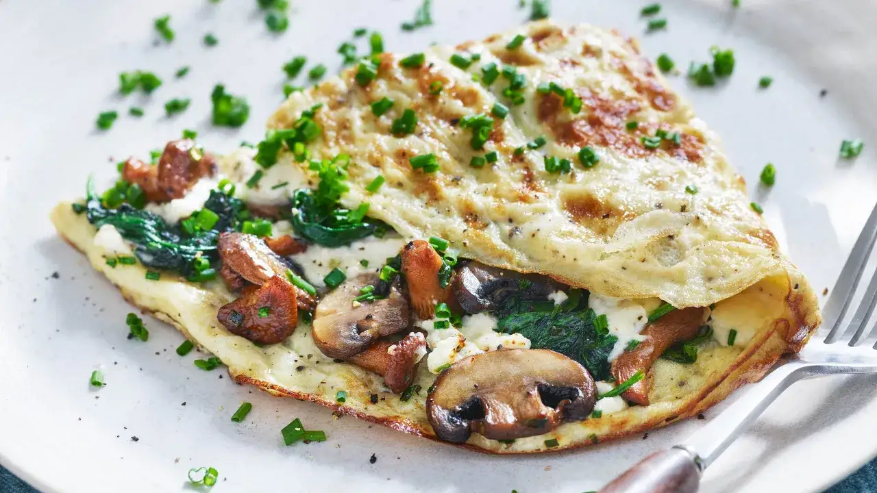 En fluffig omelett med champinjoner, spenat och ost, toppad med gräslök. En perfekt omelett med champinjoner för en god frukost eller lunch.