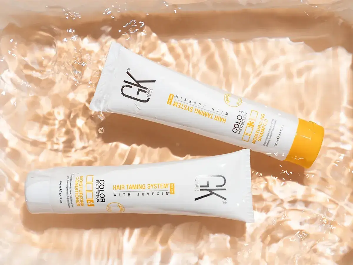 Dos tubos de GK Hair, uno de champ&uacute; y otro de acondicionador, flotan en agua clara. Descubre c&oacute;mo hidratar el pelo con estos productos.