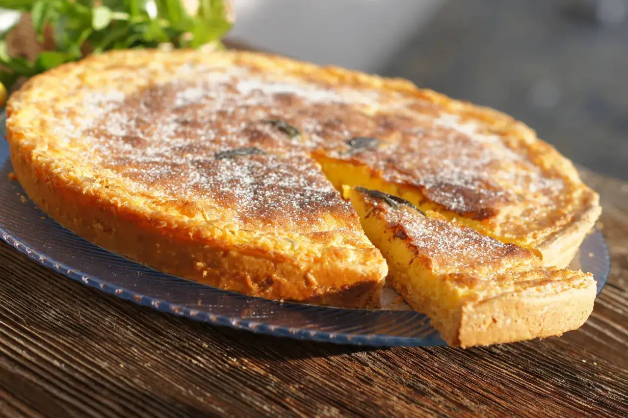 Tarta dorada con azúcar glas, un trozo cortado, como un flao ibiza.