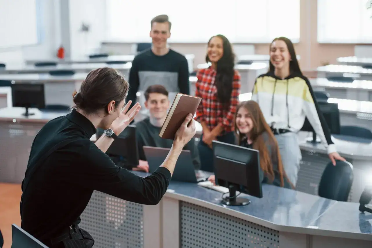 Jóvenes en un aula participan en actividades para trabajar la asertividad, interactuando con un libro y sonriendo.