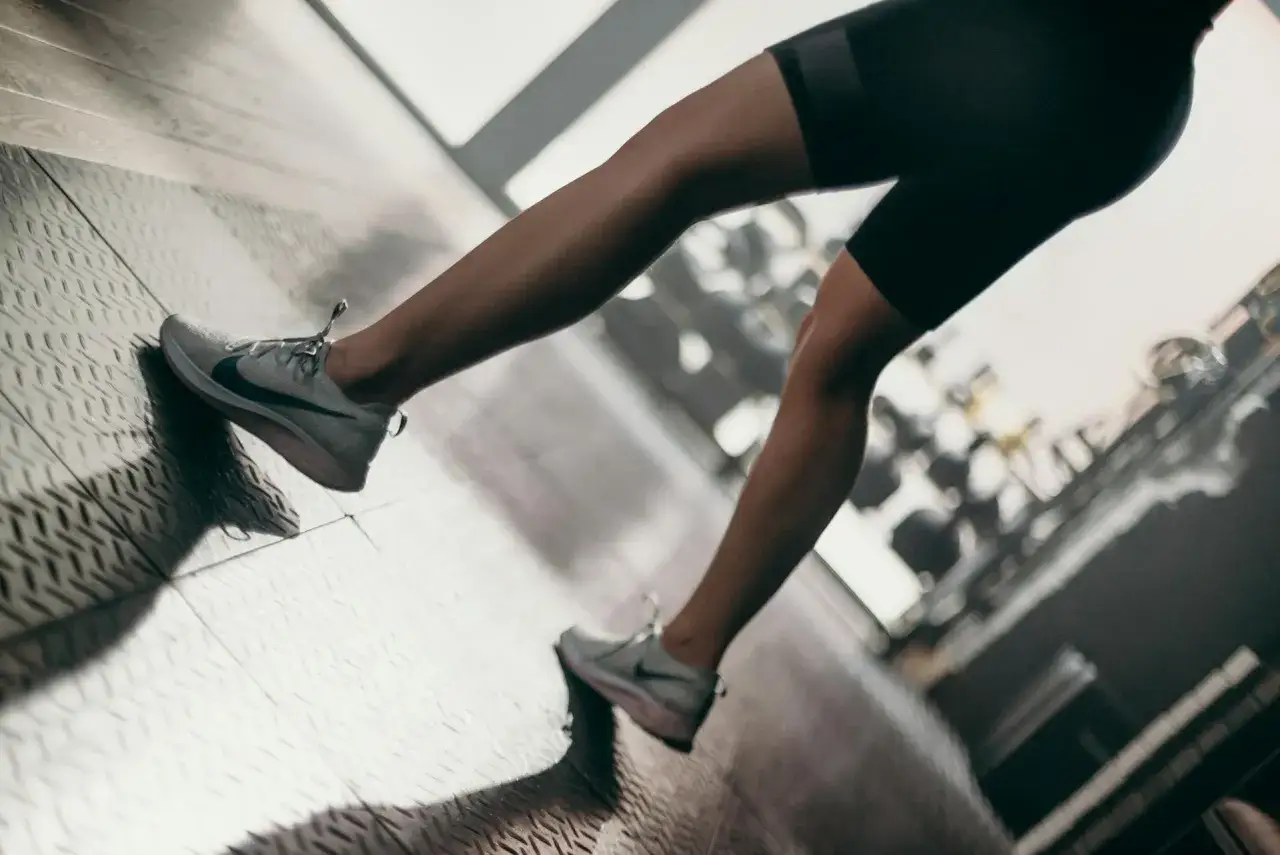Nogi biegacza w butach Nike na siłowni. Po intensywnym treningu mogą pojawić się bolące kolana po bieganiu.