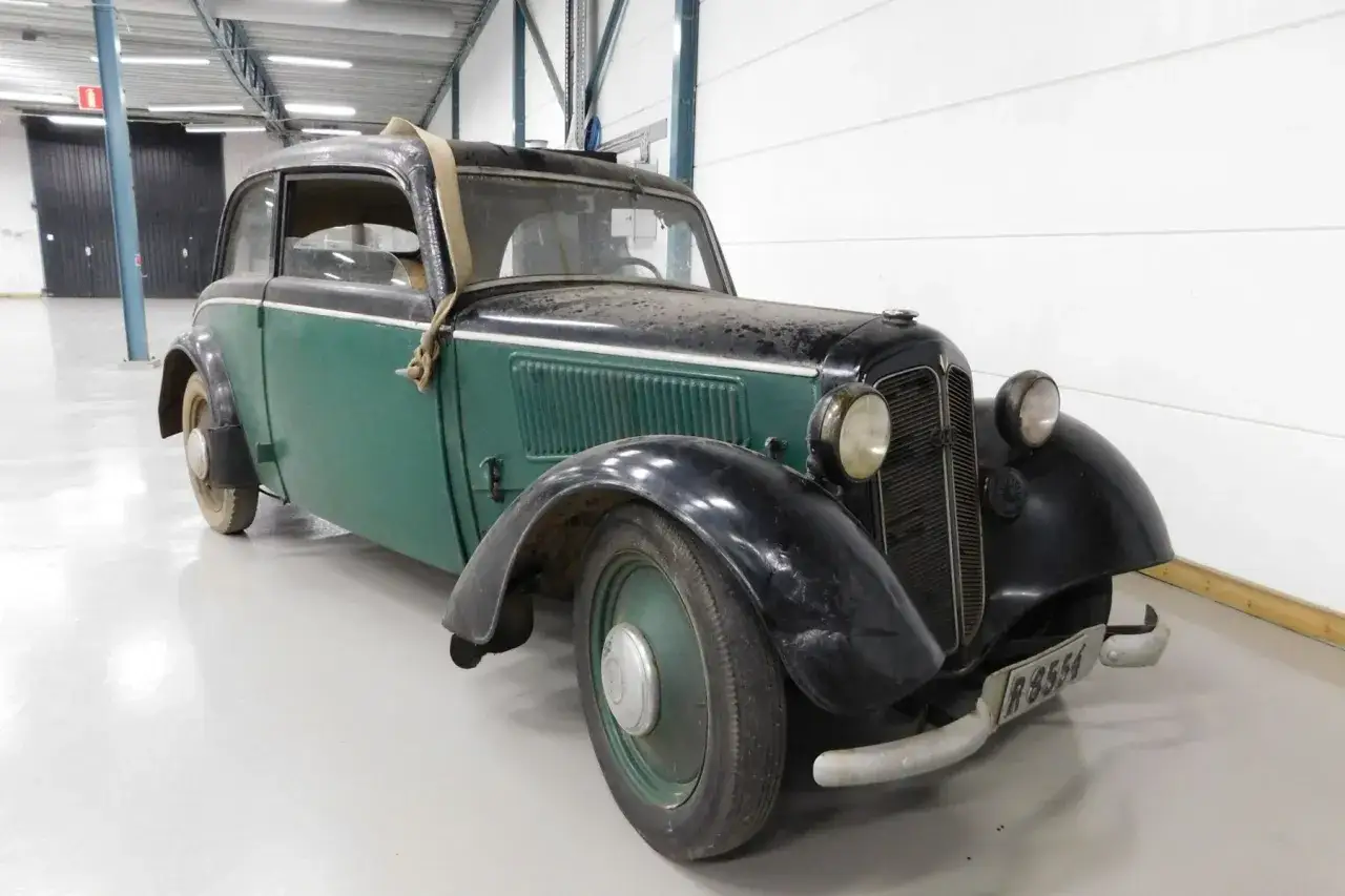 En grön och svart DKW med en spånkorgsdetalj på taket står i ett garage.
