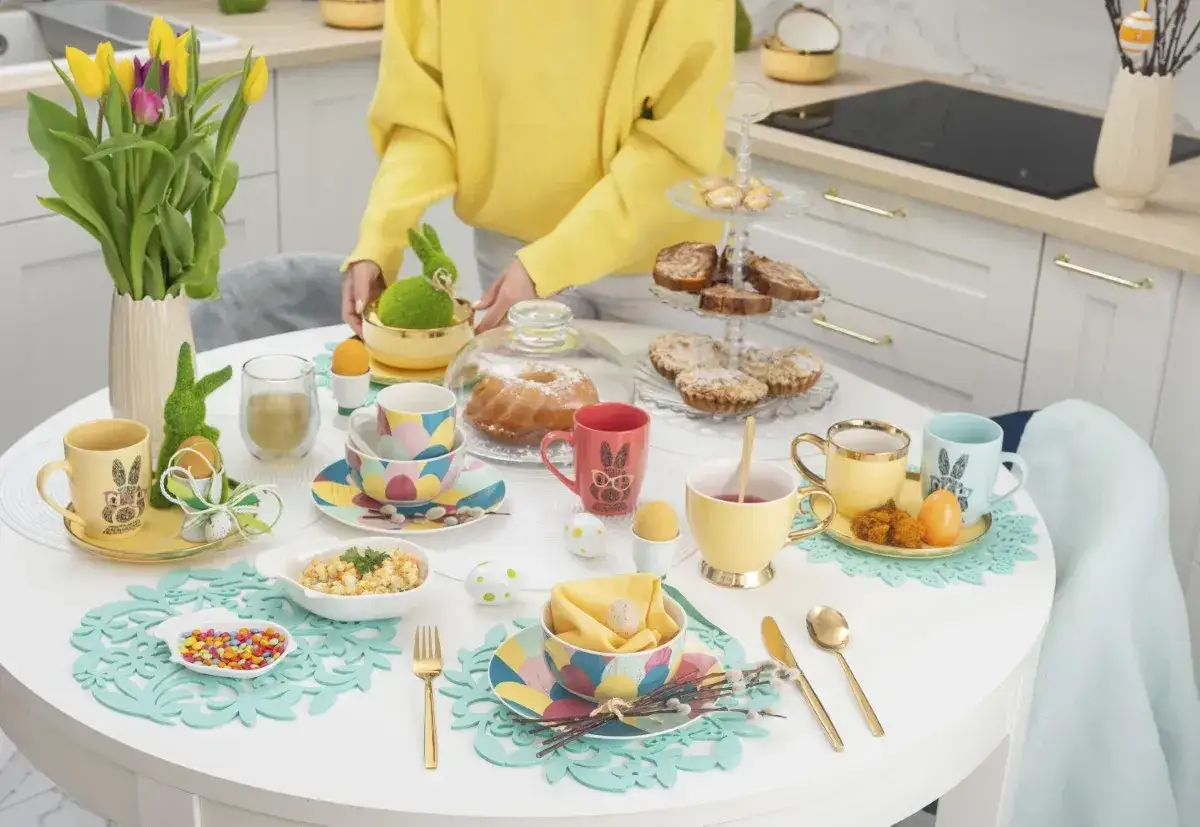 Stół zastawiony na Wielkanoc: kolorowe filiżanki, babka, ciastka, pisanki i zajączki tworzą efektowne dania wielkanocne.