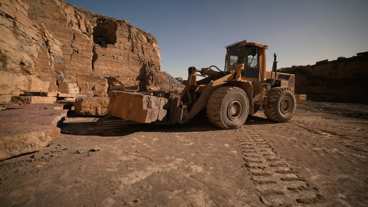 Cargadora frontal moviendo bloques de piedra en una cantera, mostrando diferentes tipos de canteras y su extracci&oacute;n.