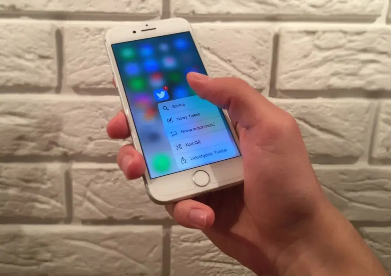 Dłoń naciska na ekran iPhone'a, aktywując menu kontekstowe aplikacji Twitter dzięki technologii 3D Touch.