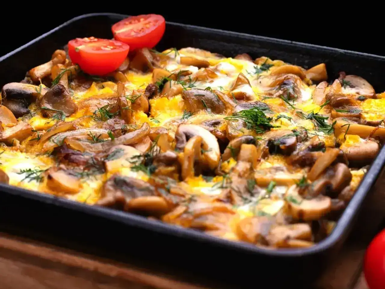 Zapiekanka z pieczarkami i serem, ozdobiona pomidorkami i koperkiem. Niskie pieczarki kcal sprawiają, że to zdrowa przekąska.