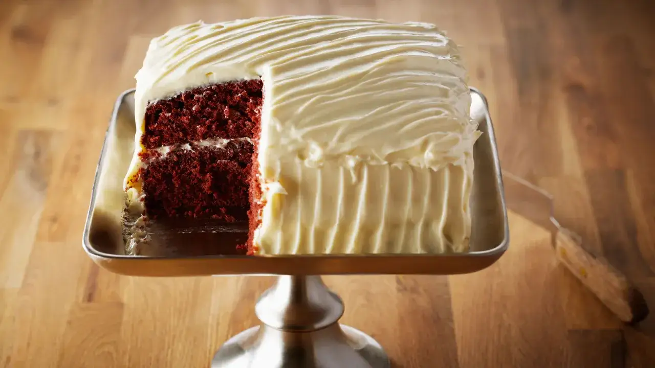 Un delicioso bizcocho red velvet con glaseado blanco cremoso, listo para ser servido.