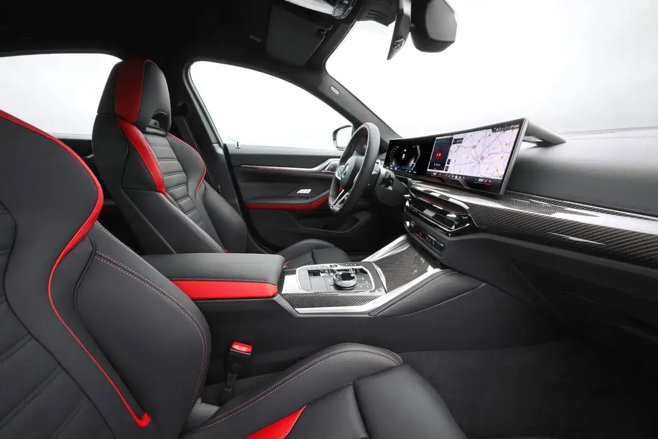 Wnętrze BMW 4 Gran Coupe z czarno-czerwonymi sportowymi fotelami i nowoczesnym panelem multimedialnym.