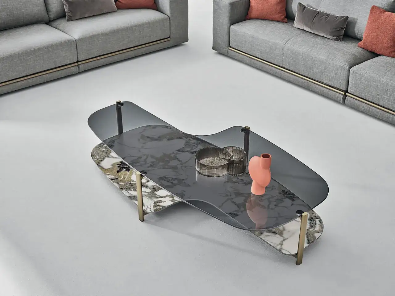 Un tavolino moderno con piano in vetro fum&eacute; e marmo, decorato con un vaso corallo e due portacandele. Perfetto per arredare il salotto, offre idee su cosa mettere sul tavolino del salotto.