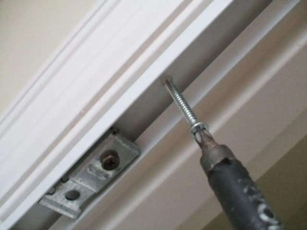 Screwdriver installing a bracket for how to install bifold doors.