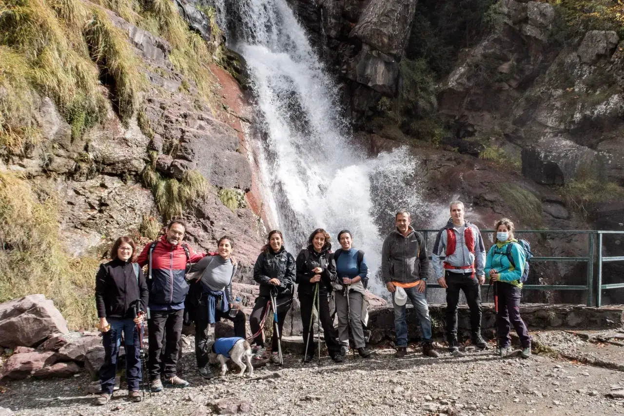 Grupo de excursionistas posa frente a la imponente cascada del Cinca, disfrutando de la naturaleza.