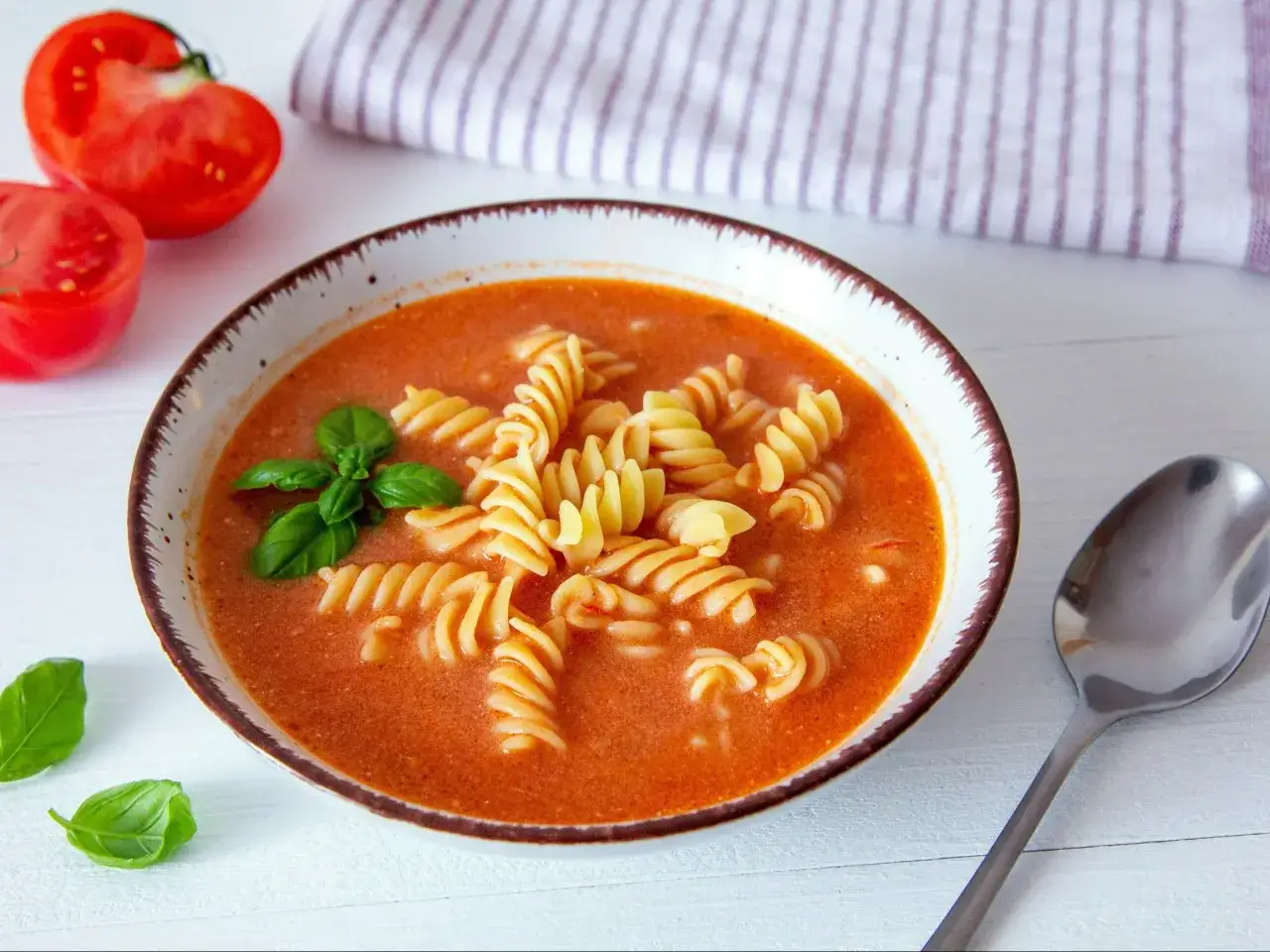 Aksamitna zupa pomidorowa z makaronem fusilli i listkami bazylii. Idealny przepis na szybki obiad.