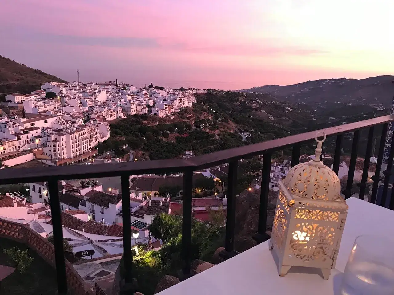Atardecer rosado sobre Frigiliana. Una linterna ilumina la mesa, perfecta para decidir dónde comer en Frigiliana.