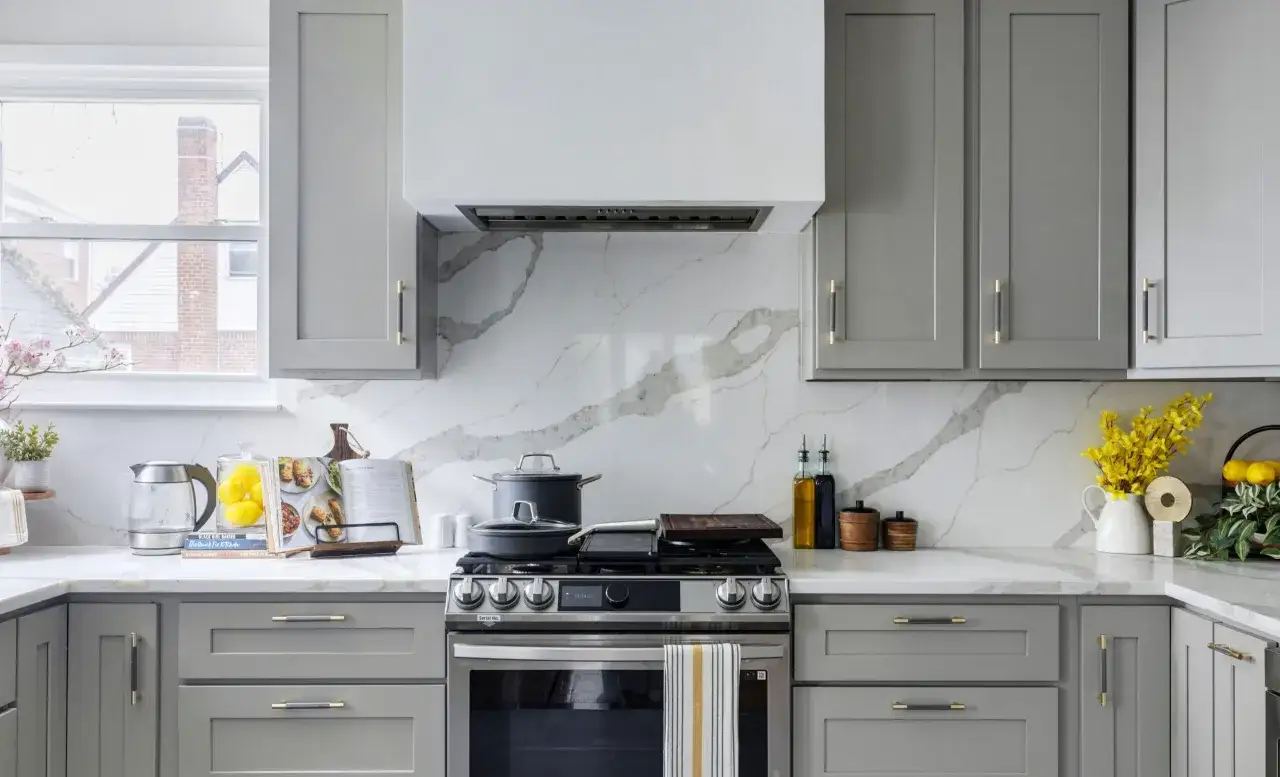 Cr&eacute;dence derri&egrave;re plaque de cuisson gaz, avec un motif marbre blanc et gris. Des casseroles sont pos&eacute;es sur la plaque.