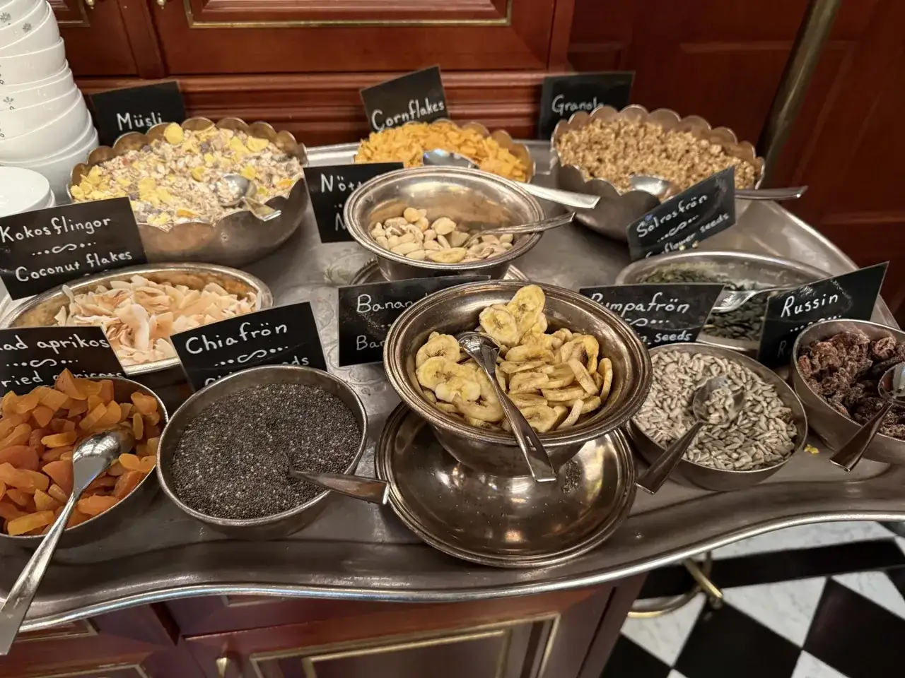 En buff&eacute; med olika tillbeh&ouml;r f&ouml;r en h&auml;rlig **bank hotell brunch**: m&uuml;sli, n&ouml;tter, torkad frukt, fr&ouml;n och flingor.