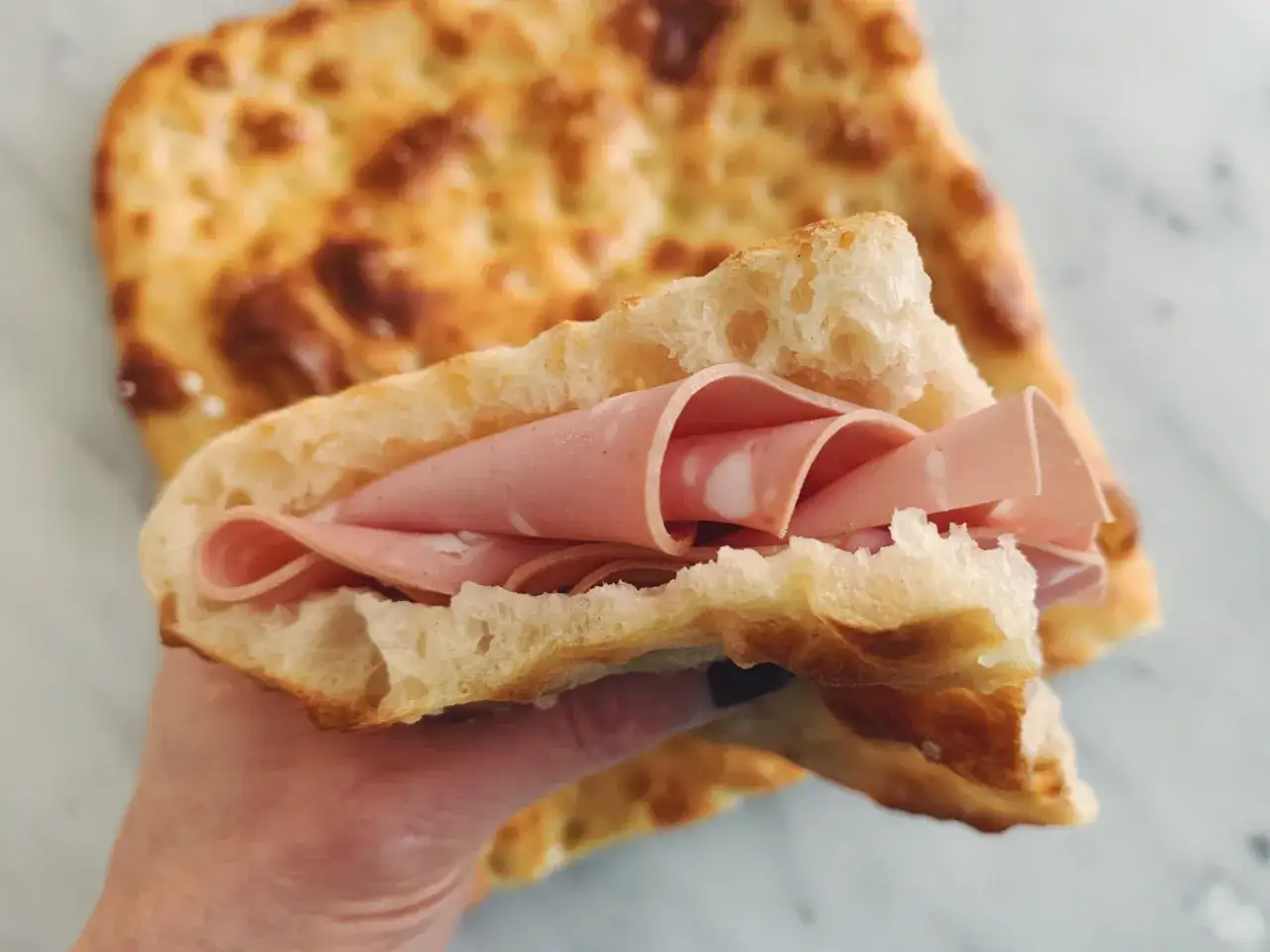 Chrupiąca focaccia z mortadelą, idealna na szybki lunch. To połączenie smaków, które przypomina włoską pizzę rossa a bianca.