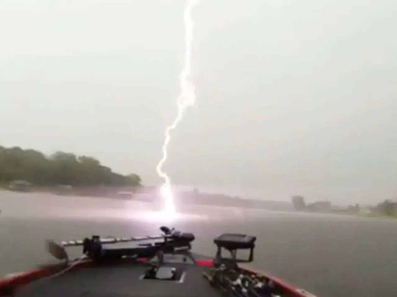 Blitz schlägt ins Wasser, während jemand auf einem Boot angelt nach Gewitter. Die Szene ist dramatisch und gefährlich.
