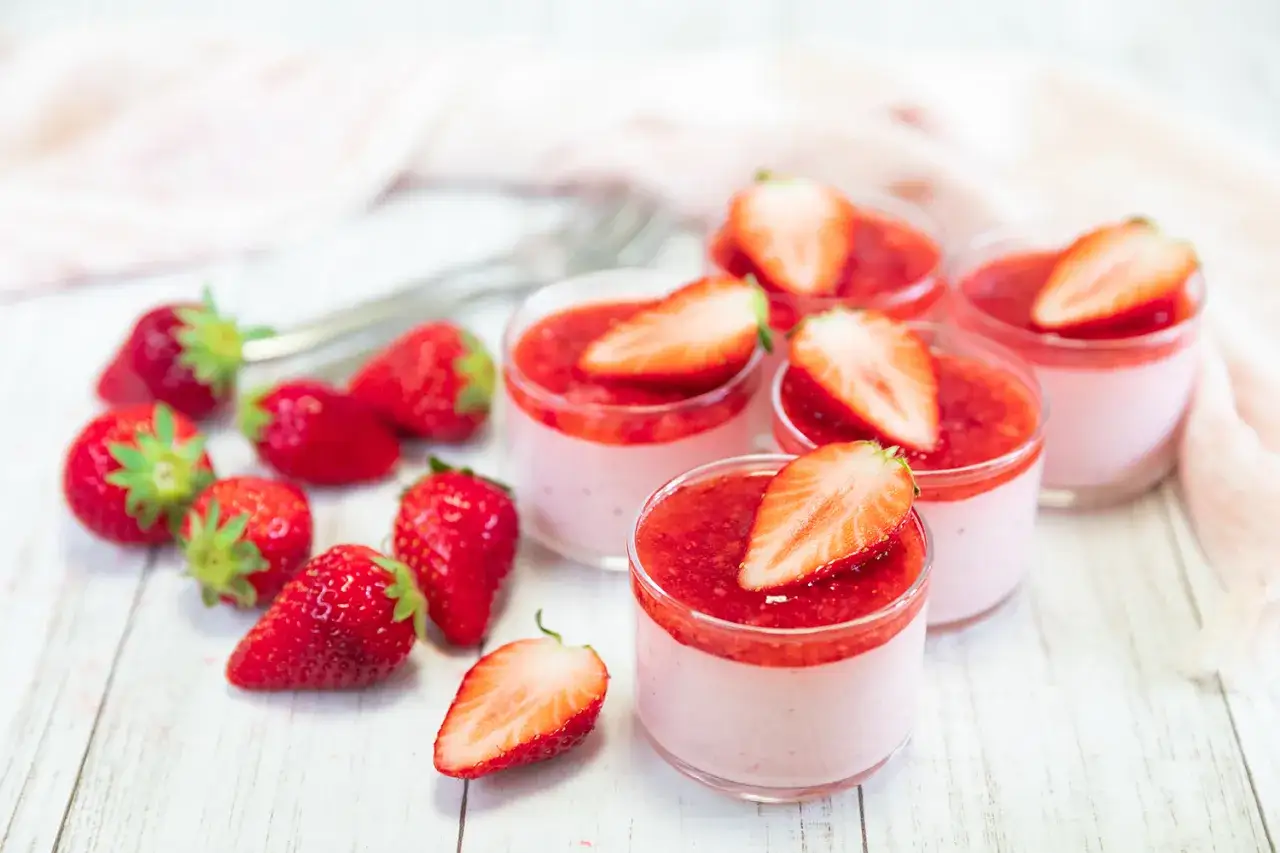 Leckeres Erdbeermus selber machen: Kleine Gläser mit rosa Creme, Erdbeersoße und frischen Erdbeeren.