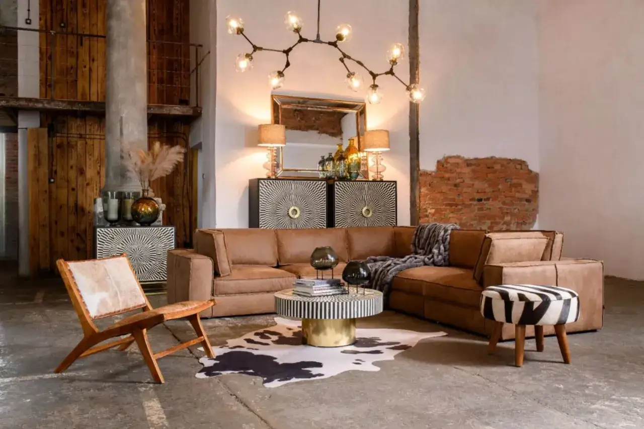 Nowoczesny salon z brązową kanapą, designerskim stolikiem i unikatowymi światłami skandynawskimi.