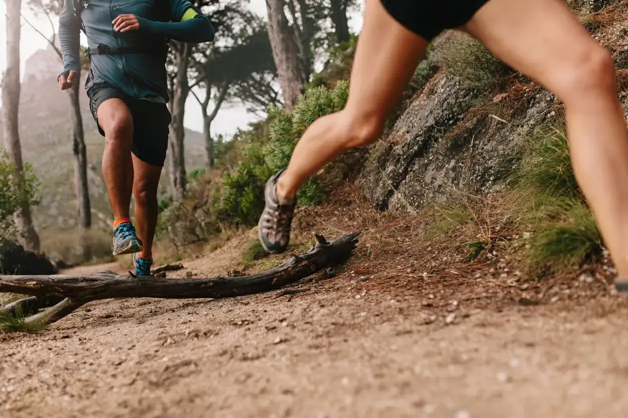 Deux coureurs s'entraînent sur un sentier de montagne. Leurs jambes musclées montrent les meilleurs exercices pour les jambes en action.