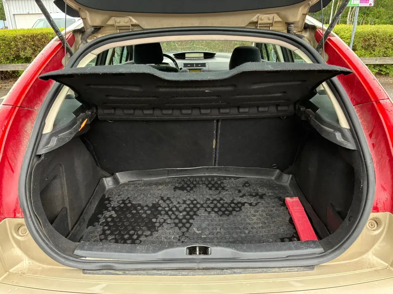 Bagageutrymmet i en begagnad Citro&euml;n C4. En gummimatta t&auml;cker golvet, med en varningstriangel i h&ouml;rnet.