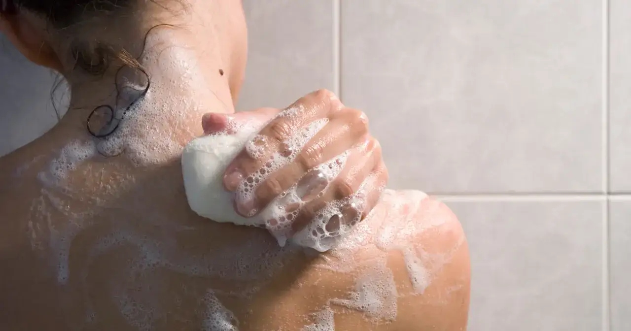 kobieta spłukująca peeling pod prysznicem