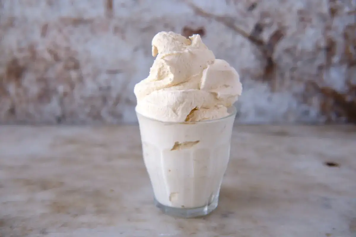 Cremiges Honig Eis in einem Glas, das auf einer Marmorplatte steht.