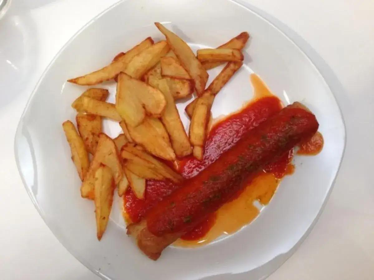 Ein Teller mit Pommes und einer Wurst, übergossen mit einer leckeren Sauce. Das ist das **Rezept Currywurst Sauce Original**!