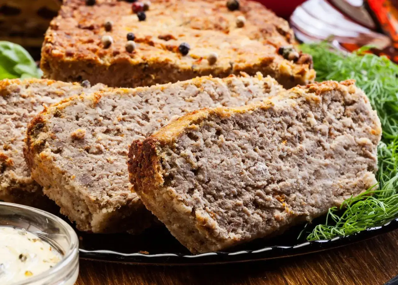 Domowy pasztet z resztek mięsa pieczonego, pokrojony w grube plastry, ozdobiony koperkiem i pieprzem. Idealny na kanapki.