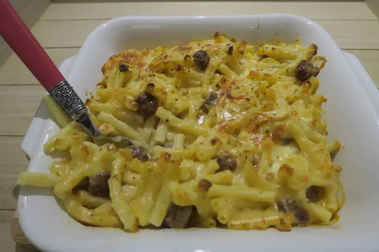 Un plat de p&acirc;tes gratin&eacute;es au reblochon, garni de viande hach&eacute;e et d'herbes. Une fourchette rose est plant&eacute;e dans le plat.