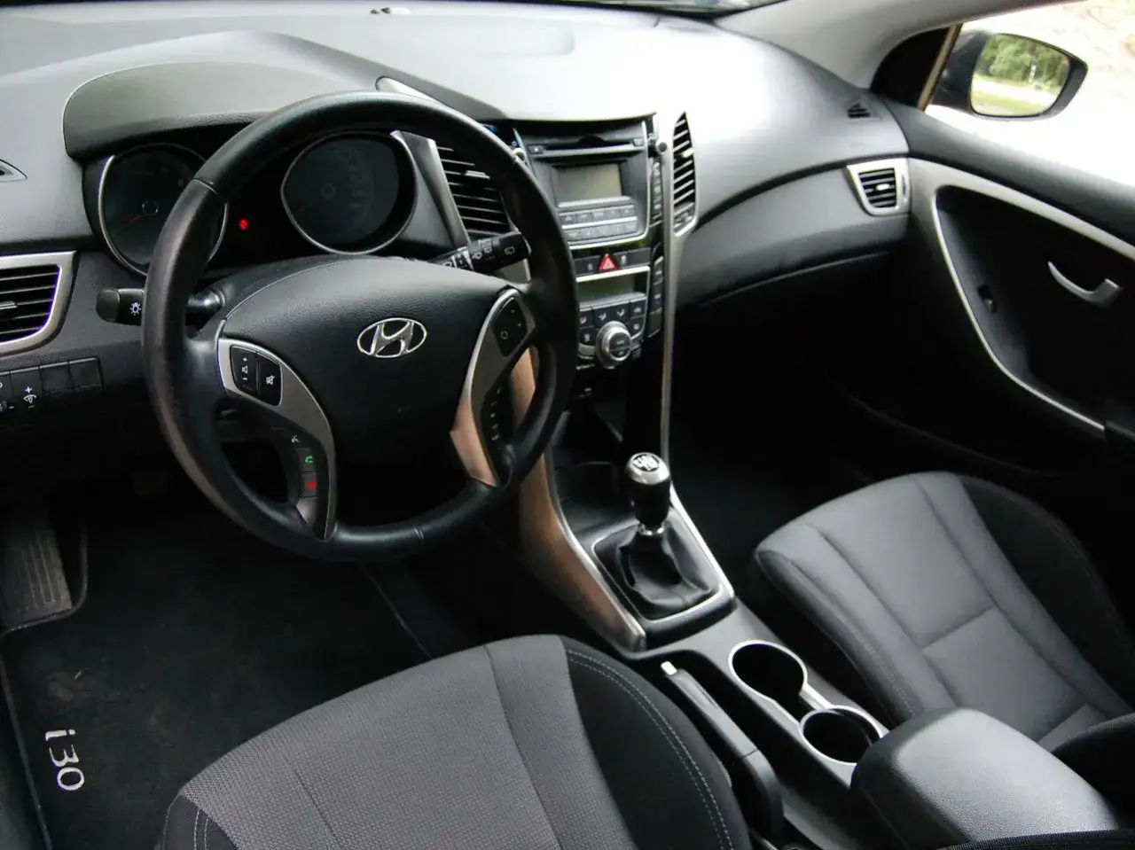 Wnętrze Hyundai i30 GD: kierownica, deska rozdzielcza, dźwignia zmiany biegów i siedzenie pasażera.
