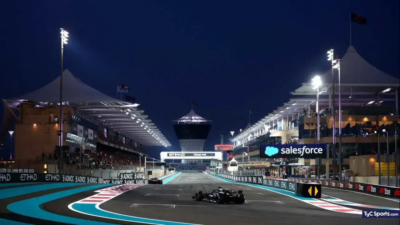 Coche de Fórmula 1 en la pista iluminada del GP Bahréin, con gradas llenas y el cielo nocturno de fondo.