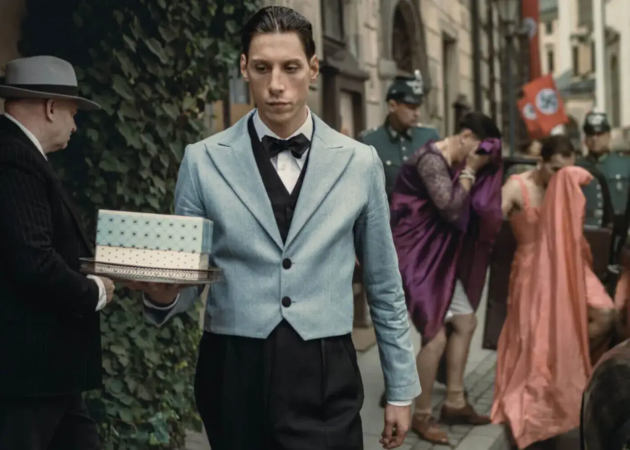 Scena z filmu, gdzie kelner niesie pudełko. W tle widać żołnierzy i kobiety w eleganckich sukniach. Filip film recenzja.