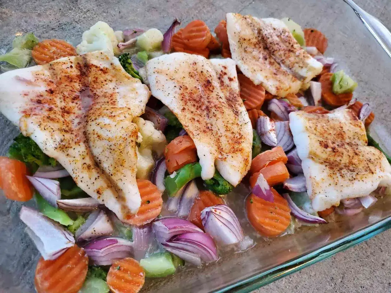 Pieczony filet rybny z warzywami: marchewką, brokułami, kalafiorem i czerwoną cebulą. Idealne danie dla osób stosujących peskatarianizm.