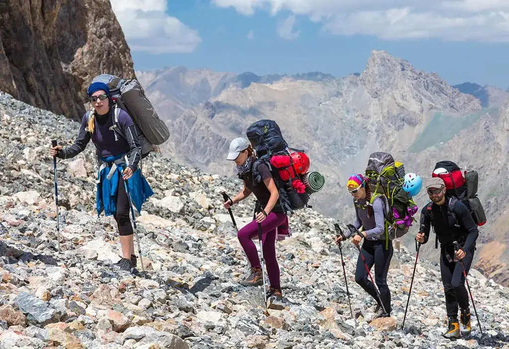 Turysta w górach z plecakiem i kijami trekkingowymi