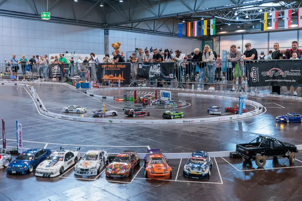 RC-Autorennen auf der **Hobby Messe Leipzig**. Viele Zuschauer bestaunen die detailgetreuen Modelle auf der Rennstrecke.