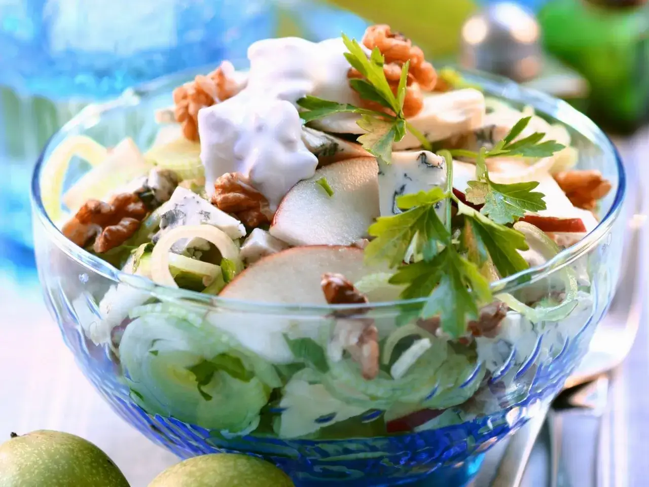 Frischer porree salat mit Äpfeln, Nüssen und Blauschimmelkäse in einer Glasschüssel, garniert mit Petersilie.