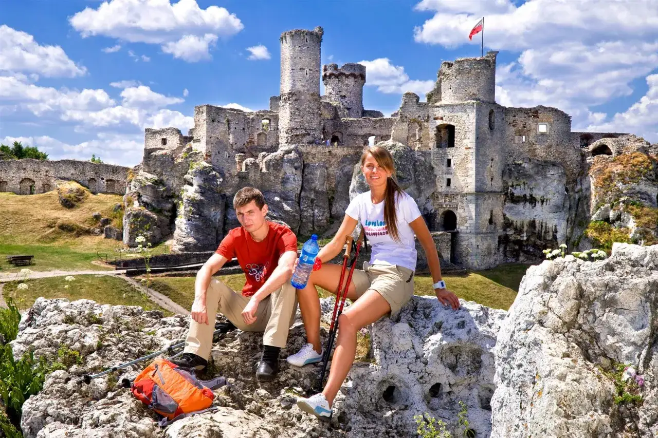 Para na tle ruin zamku Ogrodzieniec, odpoczywająca po wędrówce.