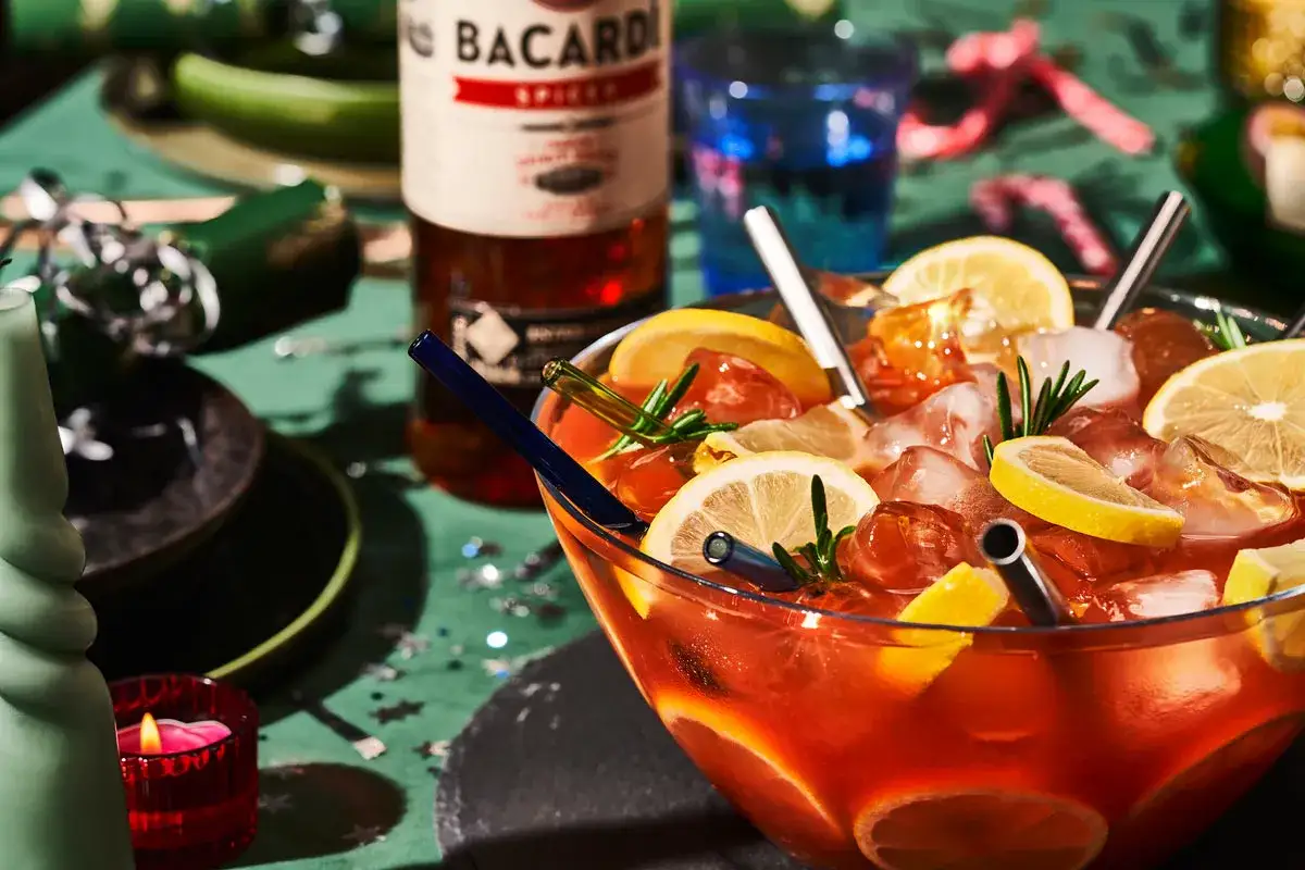 Duża misa z drinkiem z cytryną i lodem, obok butelka Bacardi Spiced. Idealne na imprezę, zastanawiasz się, bacardi spiced z czym pić?